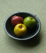 teacher gift-a top-down view of three ceramic apples of different colors on a plate.
