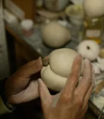 coffee table decor ideas-artisan hand-sculpting a porcelain peach in Jingdezhen