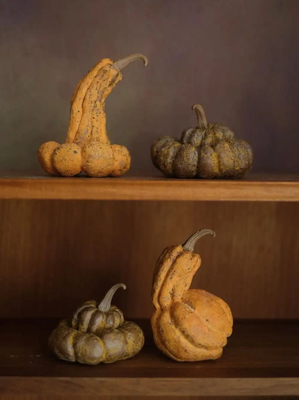 Matte handmade ceramic pumpkins in autumn tones styled on wooden shelves