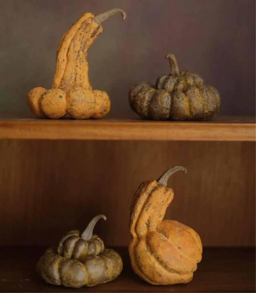 Matte handmade ceramic pumpkins in autumn tones styled on wooden shelves 01